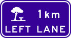 blue sign with white icon of a picnic table under a tree with text 1km left lane