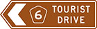 brown sign with white arrow, route number and the words tourist drive