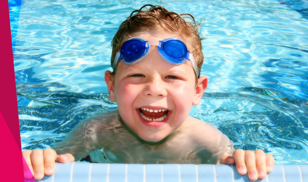 happy toddler in pool wearing goggles learning to swim