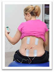 A woman holding a TENS machine and showing the electrodes in place on her back.