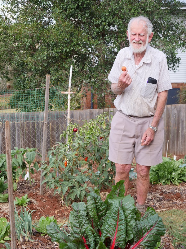Alan holding a vegetable in his outside garden. 