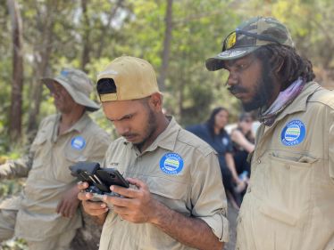 Photo of two Gunggandji-Mandingalbay Yidinji rangers use a remote control to fly a drone to monitor crocodile locations.