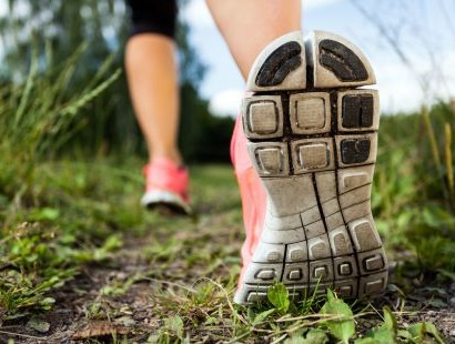 photo close up of person walking in runners along a grassy path