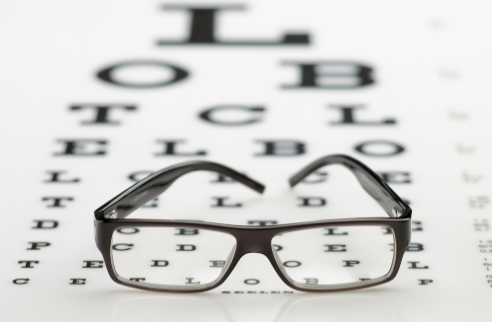 A pair of glasses placed on an eye chart
