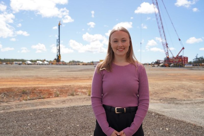 Medical Intern Christi standing in front of Bundaberg Hospital construction site. 