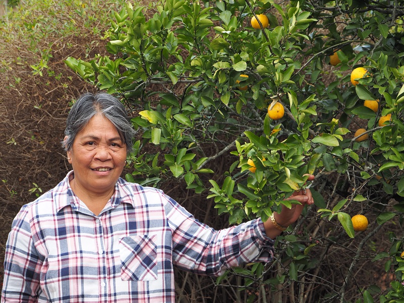 Perita standing by a lemon tree in her garden