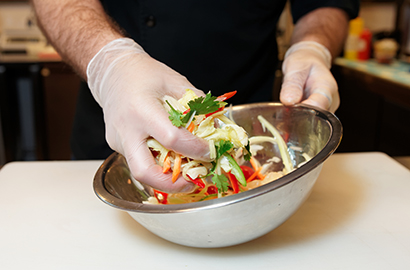 Close up of hand tossing chopped vegetables in a bowl