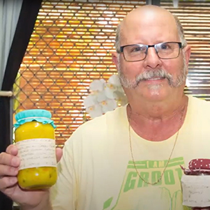 Barry, a public housing tenant, shows off two jars of preserves made from fruits in his garden.