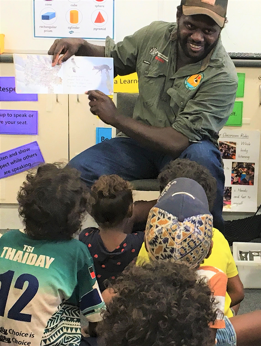 Photo of a Pormpuraaw ranger reading to young students as part of the Reading with Rangers program.