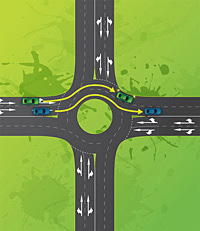 A car in the left lane approaches a roundabout and goes straight ahead, exiting the roundabout in the same left lane. Another car in the right hand lane approaches the roundabout and goes straight ahead, exiting in the same right hand lane