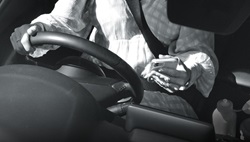 Camera showing person texting on a mobile phone while driving with one hand on the steering wheel