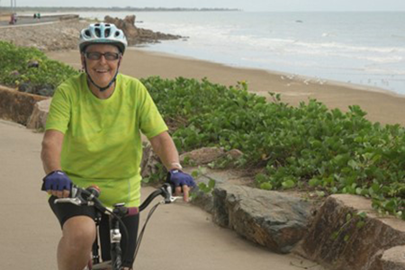 A person riding a bicycle by the ocean.