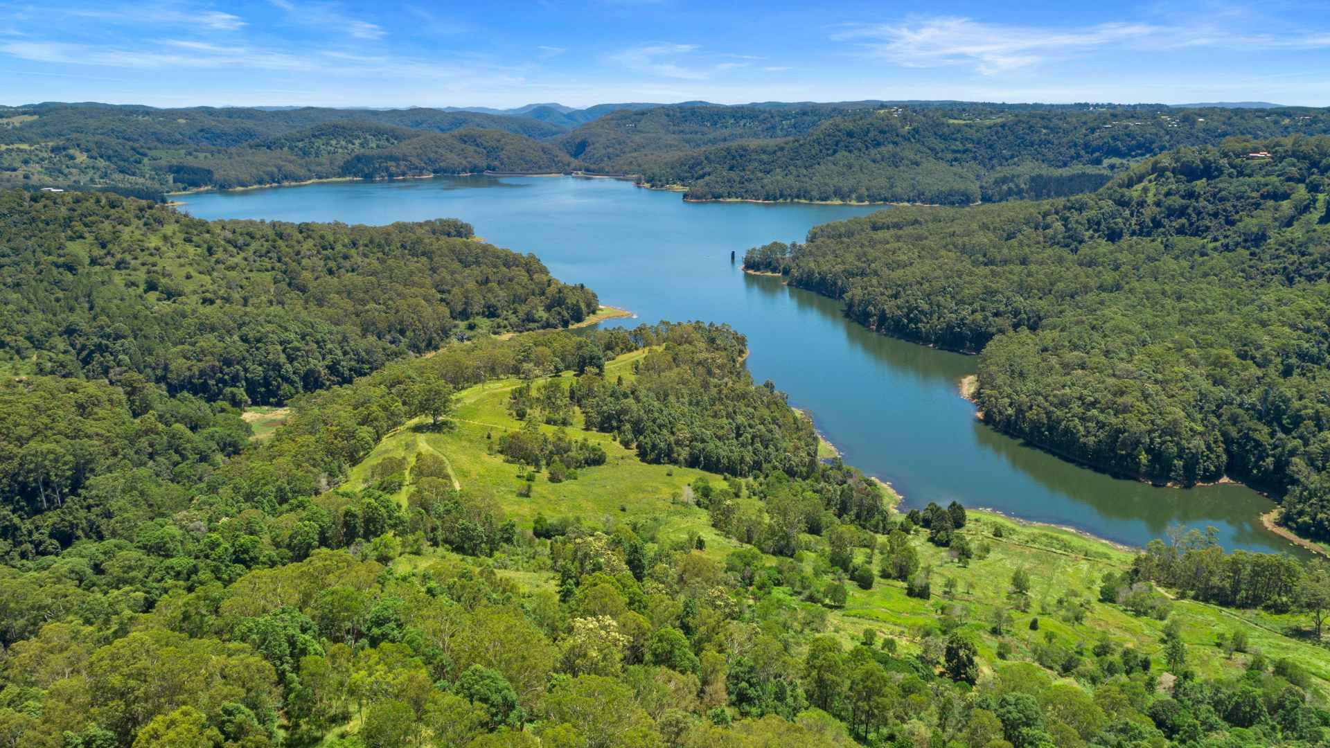 Aerial view of Baroon Pocket Dam surrounded by forested hills and farmland.