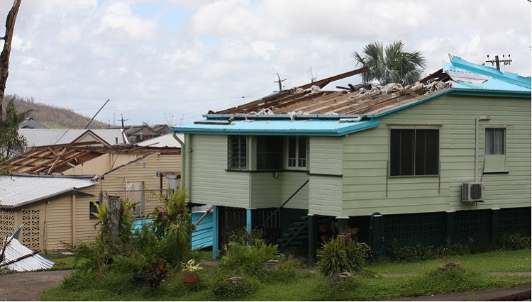 Photo of houses with roof and wall damage after a cyclone