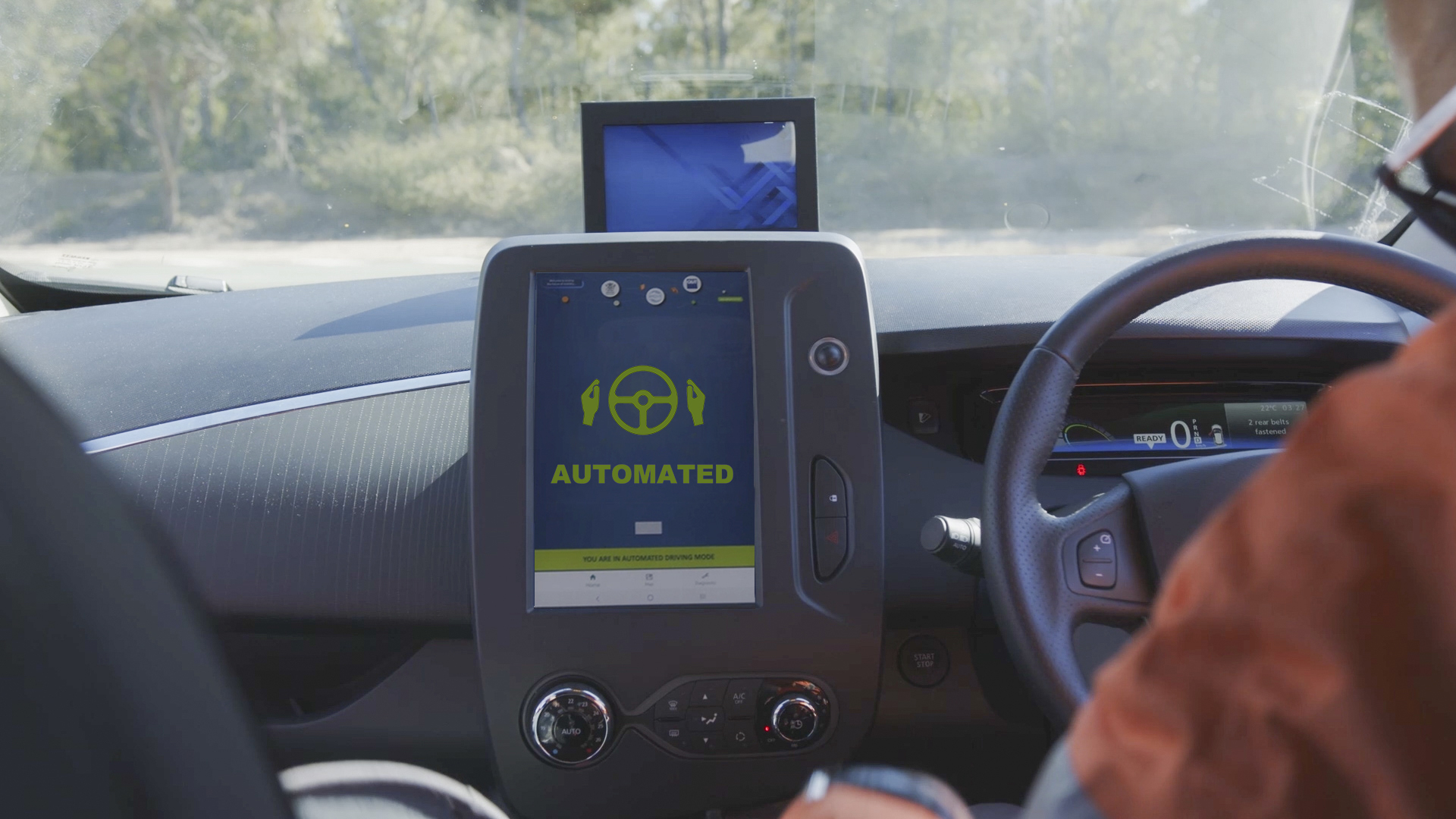 interior console of the automated vehicle ZOE2. A large display screen has a graphic showing hands off a steering wheel with the word "Automated" below.