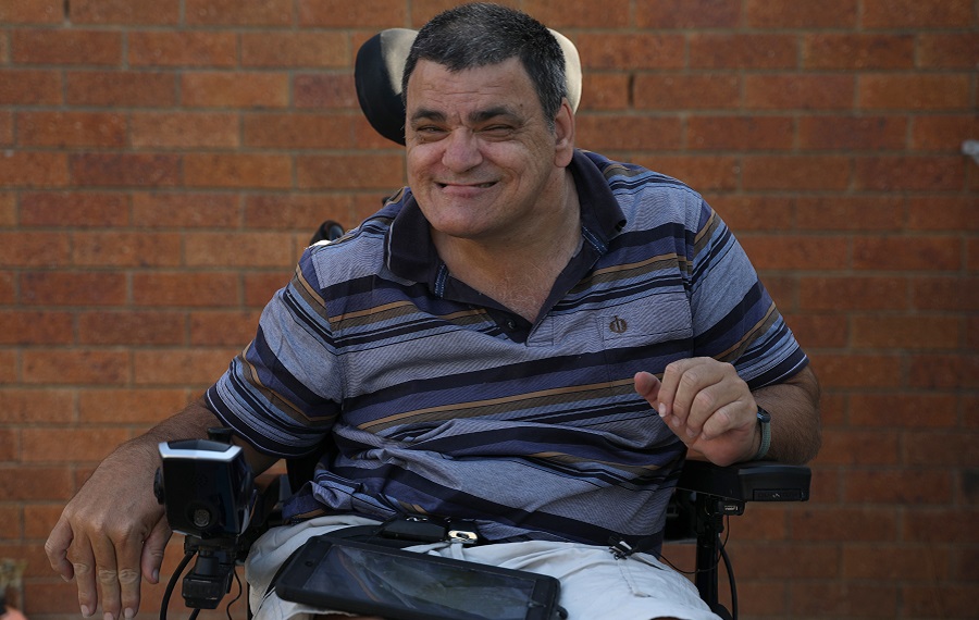 photo of Simon in his wheelchair with red brick wall in background