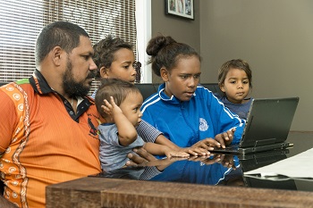 Family sitting around a laptop 