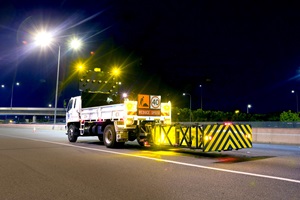 Truck with bright variable message signage and safety barriers with bright diagonal lines in black and vivid yellow