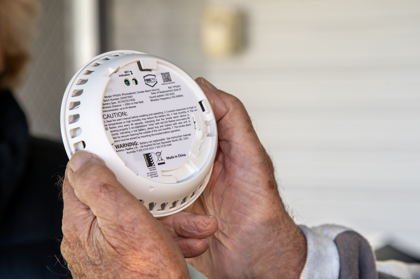A person holds a smoke alarm.