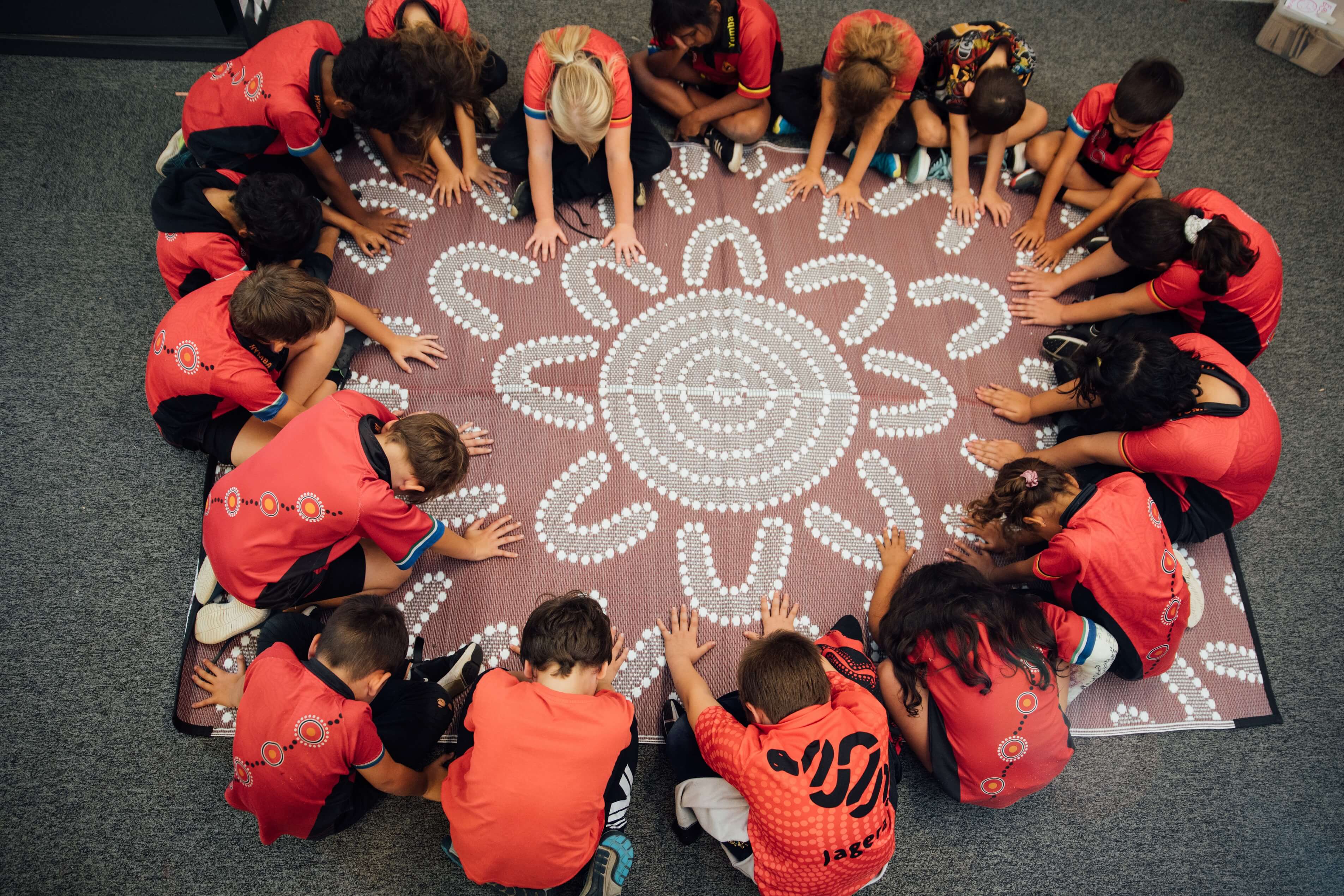 Hymba Yumba students sitting in a group working on Aboriginal artwork