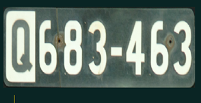 Black rectangular vehicle registration plate with large white 'Q' followed by 6 numbers