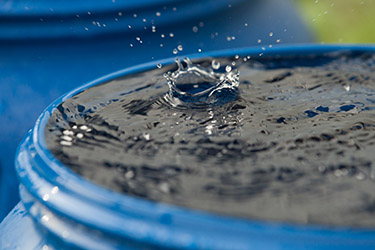 A blue container, full of water, has a droplet splash